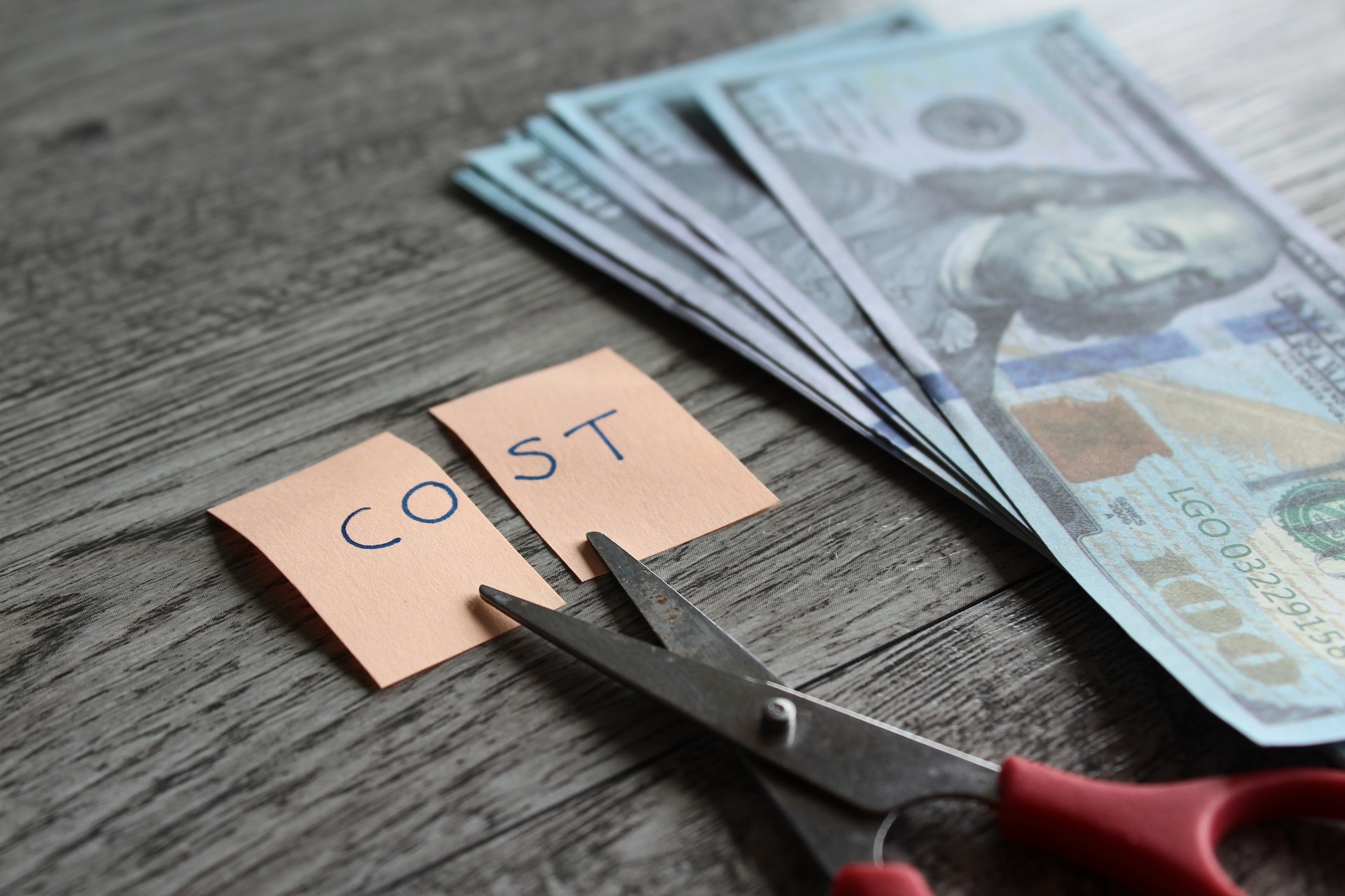 Scissor, money and note with text COST.